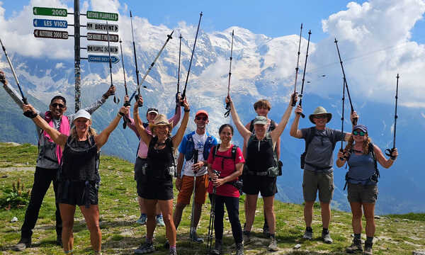 A group of hikers holding their poles in the air and smiling