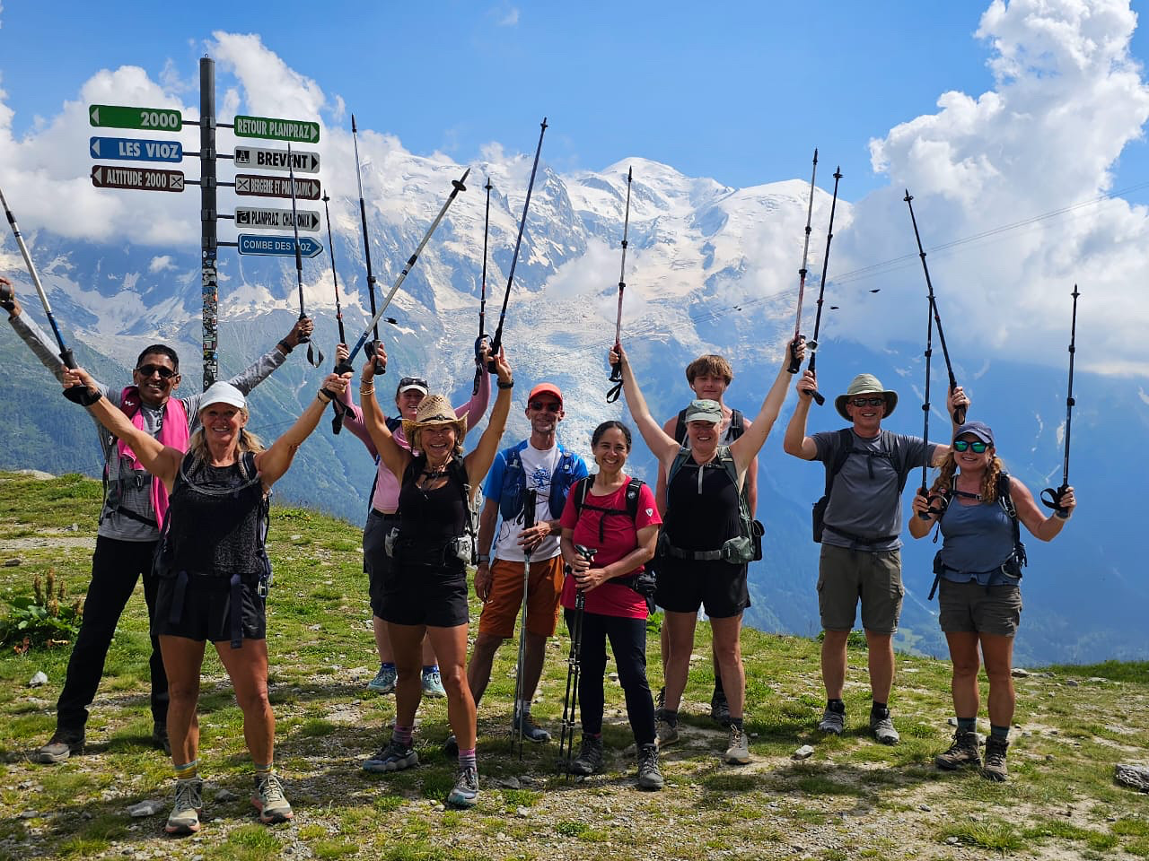 A group of hikers holding their poles in the air and smiling