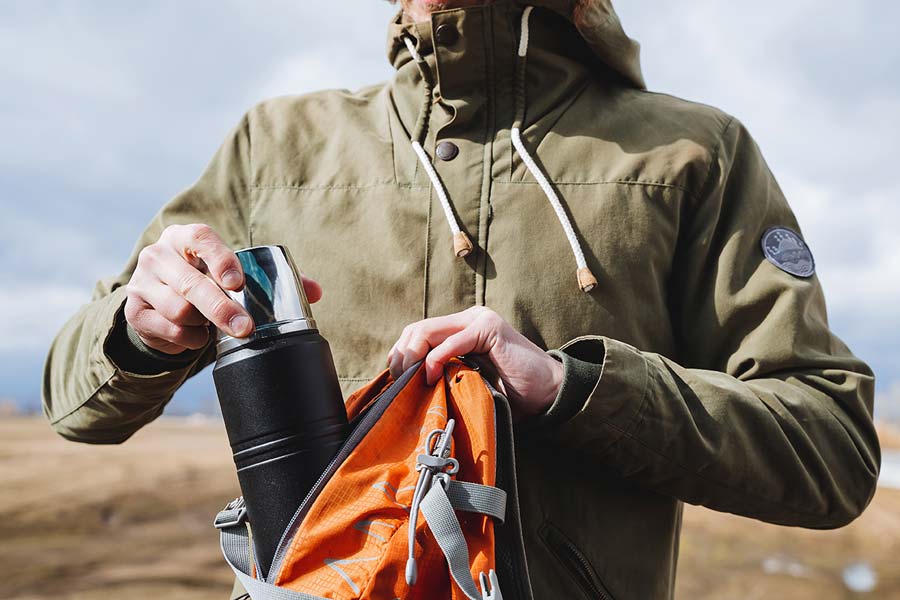 A hiker putting a flask in her rucksack